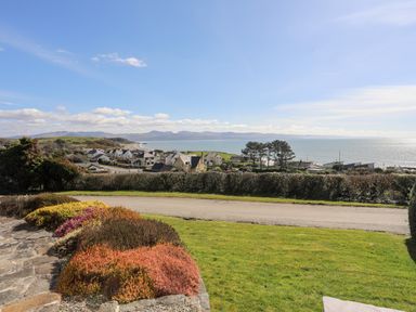 A coastal village with houses near the sea and hills in the background at Bryn Deryn in Criccieth