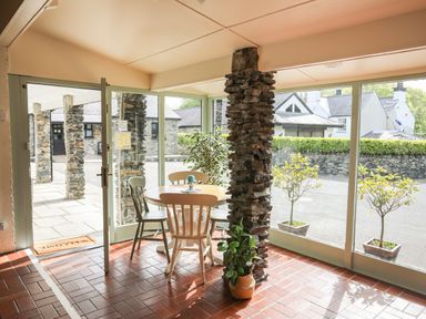 A dining area with a round table and four chairs next to stone pillars and large windows at Bryn Eira Stables Llanfair PG