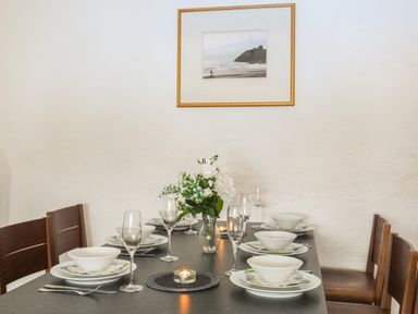 A dining table set with plates bowls glasses cutlery and a flower vase under a framed picture at Bryn Eira Stables in Llanfair PG