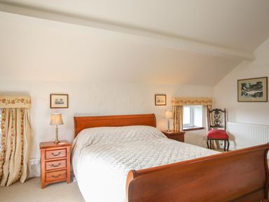 A bedroom with a wooden bed and nightstands with lamps at Bryn Eira Stables in Llanfair PG