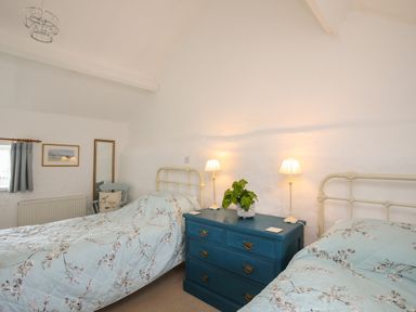 A bedroom with two beds blue floral bedding a blue dresser with lamps and a plant at Bryn Eira Stables in Llanfair PG