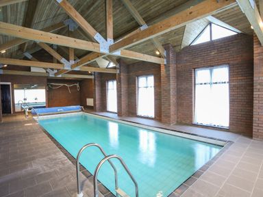 An indoor swimming pool with metal handrails and brick walls at Bryn Eira Stables Llanfair PG