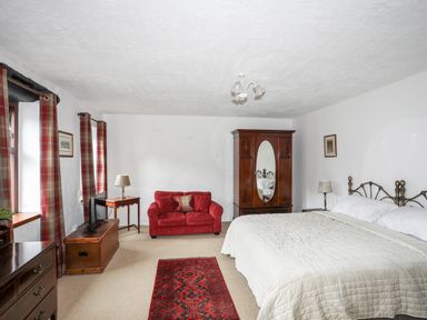 A bedroom with a bed sofa wardrobe TV and red carpet at Bryn Eira Stables in Llanfair PG