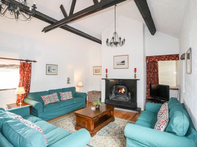 A living room with teal sofas a wooden coffee table and a fireplace at Bryn Eira Stables in Llanfair PG