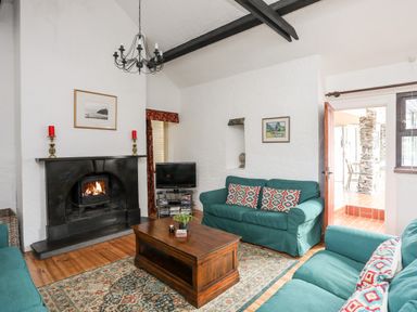 A living room with green sofas around a wooden coffee table and a fireplace at Bryn Eira Stables in Llanfair PG