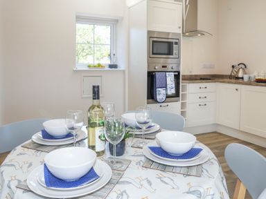 A kitchen with a dining table set with bowls glasses and wine at Bwthyn Glanrhyd in Llanfair yn Neubwll