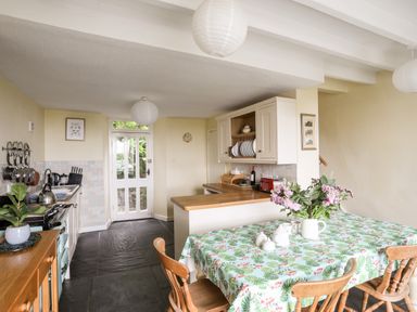 A kitchen with wooden dining table and chairs and kitchen cabinets at Bron Castell in Harlech