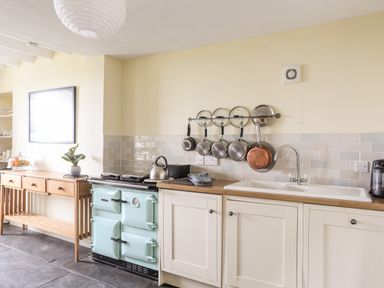 A kitchen with a light blue stove wooden countertop and hanging pots at Bron Castell in Harlech