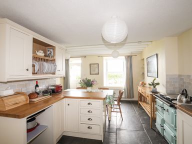 A kitchen with wooden countertops a dining table with chairs a light blue stove and hanging paper lanterns at Bron Castell in Harlech