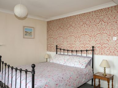 A bedroom with an iron bed frame a floral bedspread two bedside tables with lamps and a framed picture on the wall at Bron Castell in Harlech