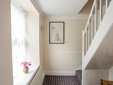 A stairway with striped carpet and a vase with flowers on a windowsill at Bron Castell in Harlech