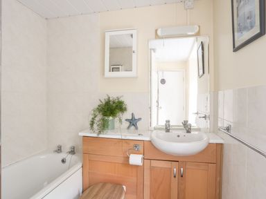 A bathroom with a bathtub sink wooden cabinet mirror and a potted plant at Bron Castell in Harlech
