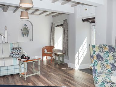 A living room with a sofa table camera chair and patterned armchair at Brook Cottage in Criccieth