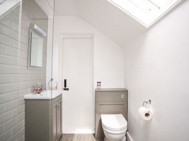 A bathroom with a toilet a sink and a mirror under a skylight at Brook Cottage in Criccieth