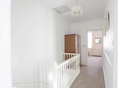 A hallway with white railing a wooden wardrobe and door leading to another room at Bro Dawel in Beaumaris