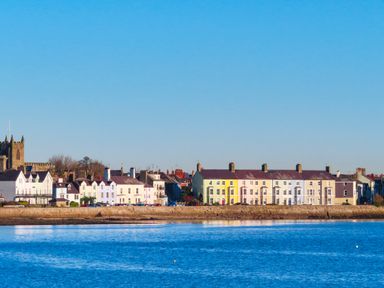 A row of colorful houses and a church along a waterfront at Bro Dawel in Beaumaris