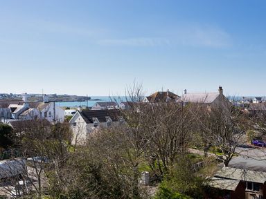 A coastal residential area with houses trees and a view of the sea at Bryn Dale in Trearddur Bay