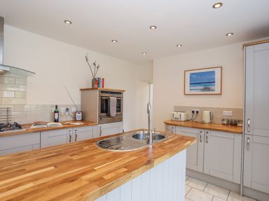 A kitchen with wooden countertops a sink an oven a toaster kettle and cabinets at Bryn Dale in Trearddur Bay