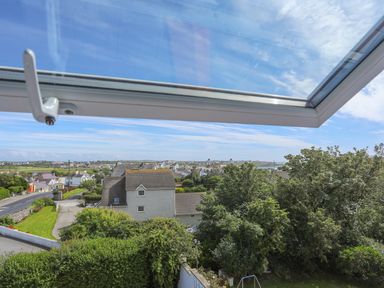 A view through an open window showing houses trees and a road in a residential area at Bryn Dale in Trearddur Bay