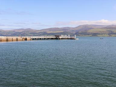 A pier extending into a body of water with hills in the background at Bryn Tegid in Beaumaris