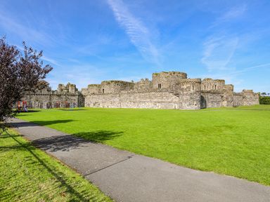 A stone castle with a large grassy area and playground equipment at Bryn Tegid in Beaumaris