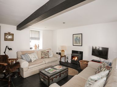 A living room with two beige sofas a wooden armchair a coffee table and a fireplace at Bryn Tegid in Beaumaris