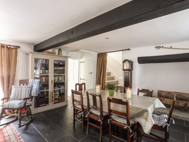A dining room with a long table and wooden chairs a rocking chair and a glass cabinet at Bryn Tegid in Beaumaris