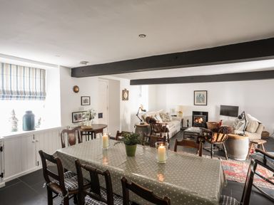 A dining area with a long table and candles and a living area with sofas and a fireplace at Bryn Tegid in Beaumaris