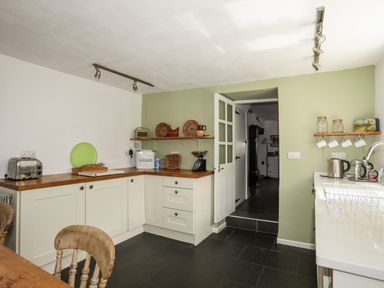 A kitchen with white cabinets wooden countertops and various kitchen items at Bryn Tegid in Beaumaris