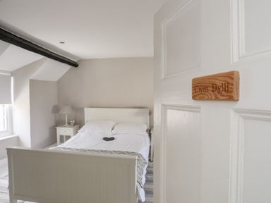 A bedroom with a white bed side tables lamp and a window at Bryn Tegid in Beaumaris