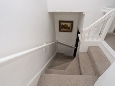 A carpeted staircase with white walls and a painting on the wall at Bryn Tegid in Beaumaris