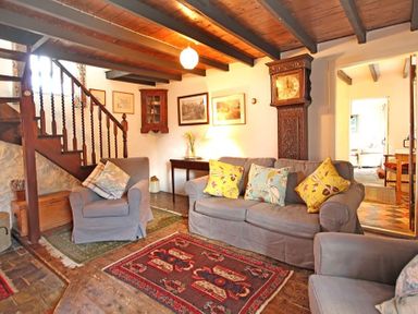 A living room with armchairs a sofa and a grandfather clock at Buck Cottage in Red Wharf Bay