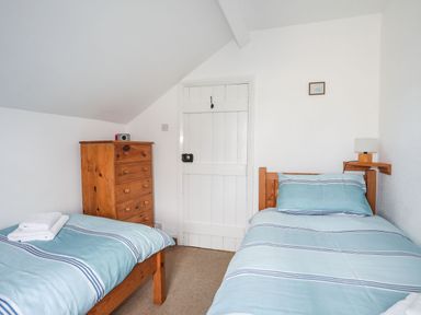A bedroom with two single beds and a wooden chest of drawers at Cae Person in Llangoed