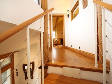 A wooden staircase with metal cables and handrails leading to a wooden hallway at Cae'r Dyni Criccieth