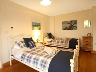 A bedroom with two single beds with blue plaid bedding and anchor pillows at Cae'r Dyni (Caer Dyni) in Criccieth