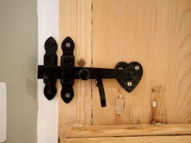 A close up of a black metal latch on a wooden door at Cae'r Dyni (Caer Dyni) in Criccieth