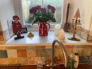 A kitchen counter with a kettle flowers and Christmas decorations at Cae'r Dyni (Caer Dyni) Criccieth