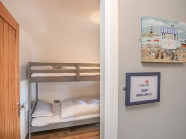 A small bedroom with a gray bunk bed and wooden door at Cambrian House in Criccieth