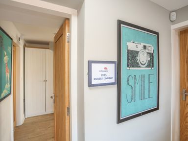 A hallway with wooden doors and framed pictures on the walls at Cambrian House in Criccieth