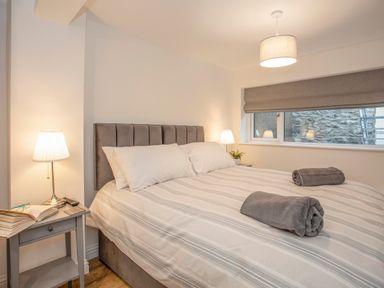 A bedroom with a bed with rolled towels on it bedside tables with lamps a window with a blind at Cambrian House in Criccieth