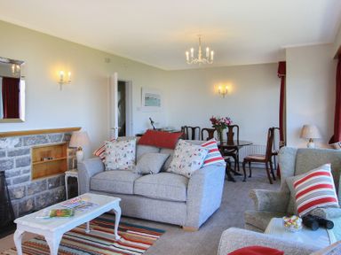 A living room with sofas cushions a coffee table and a dining table with chairs at Camlan in Beaumaris