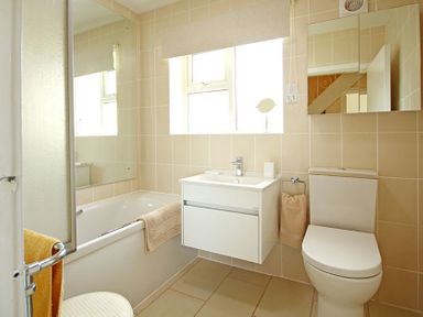 A bathroom with a bathtub sink toilet and mirror at Camlan in Beaumaris