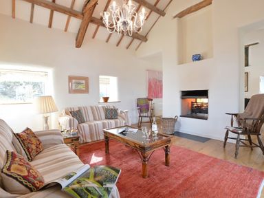 A living room with a fireplace two couches wooden chairs a chandelier and a coffee table at Cefn Isaf in Porthmadog