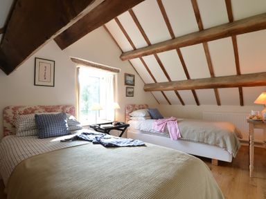 A bedroom with two single beds wooden ceiling beams and a window with curtains at Cefn Isaf in Porthmadog
