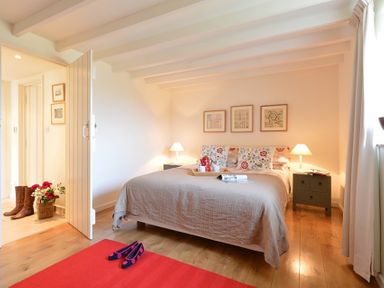 A bedroom with a bed lamps on bedside tables and shoes on a red rug at Cefn Isaf in Porthmadog