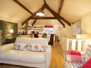 A living room and kitchen area with wooden beams and furniture at The Coach House - Beaumaris