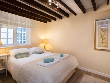 A bedroom with a double bed two bedside tables lamps and a framed picture on the wall at The Coach House - Beaumaris