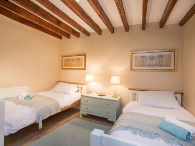 A bedroom with two single beds a nightstand with lamps and framed pictures on the wall at The Coach House Beaumaris