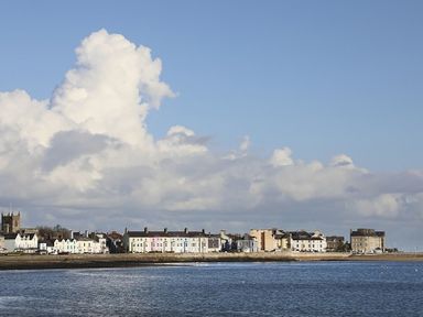 A coastal town with buildings along the shoreline and a church visible in the distance at The Coach House - Beaumaris in Beaumaris