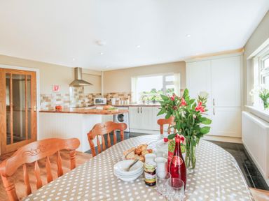 A kitchen with a dining table set with flowers and breakfast items at Coed Bolyn Lodge in Bethel